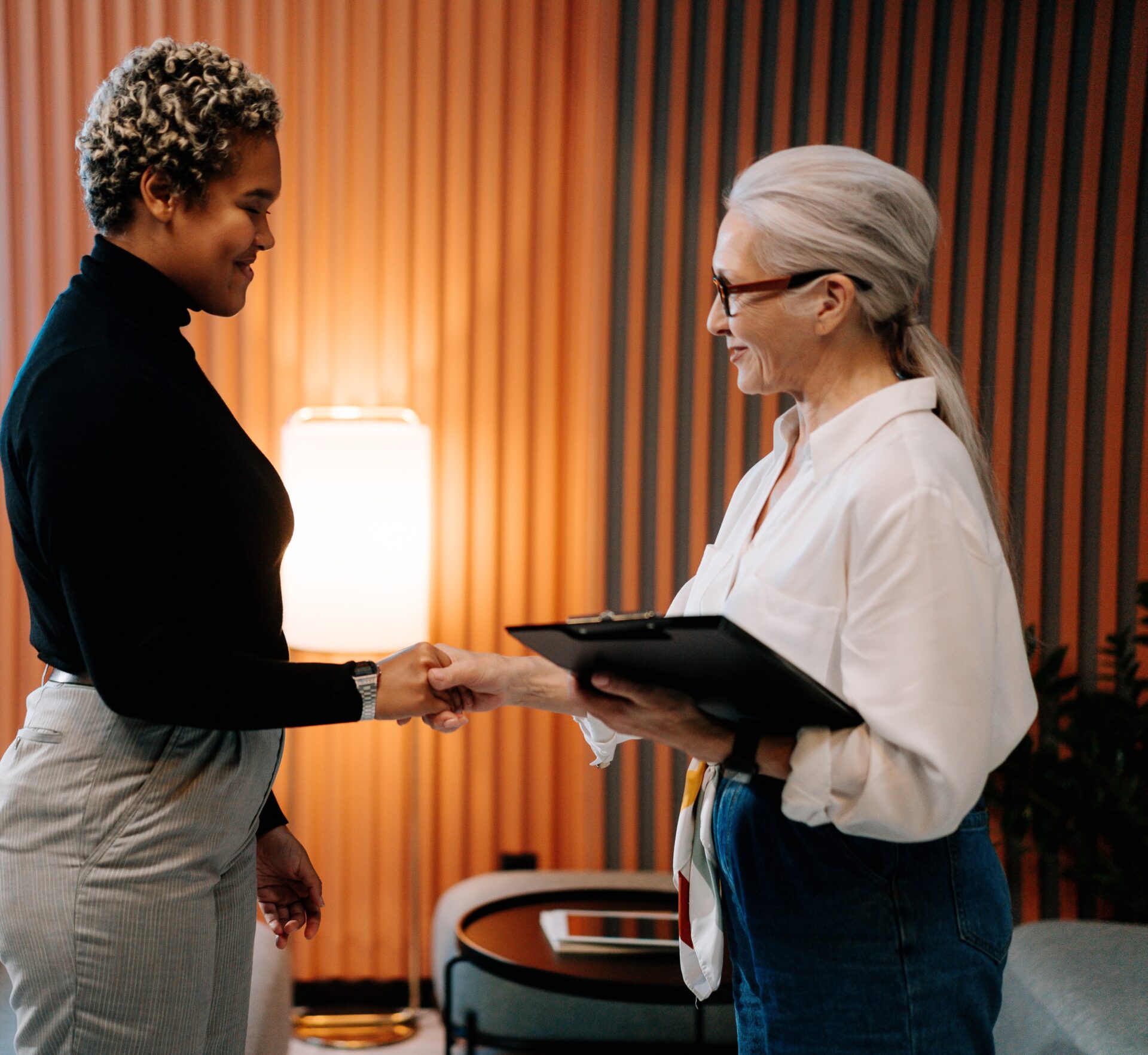 black woman shakes older professional woman's hand in an office setting