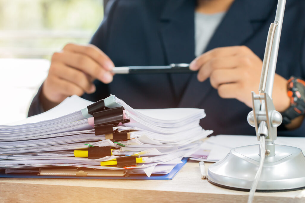 man holds pen over stack of legal paperwork