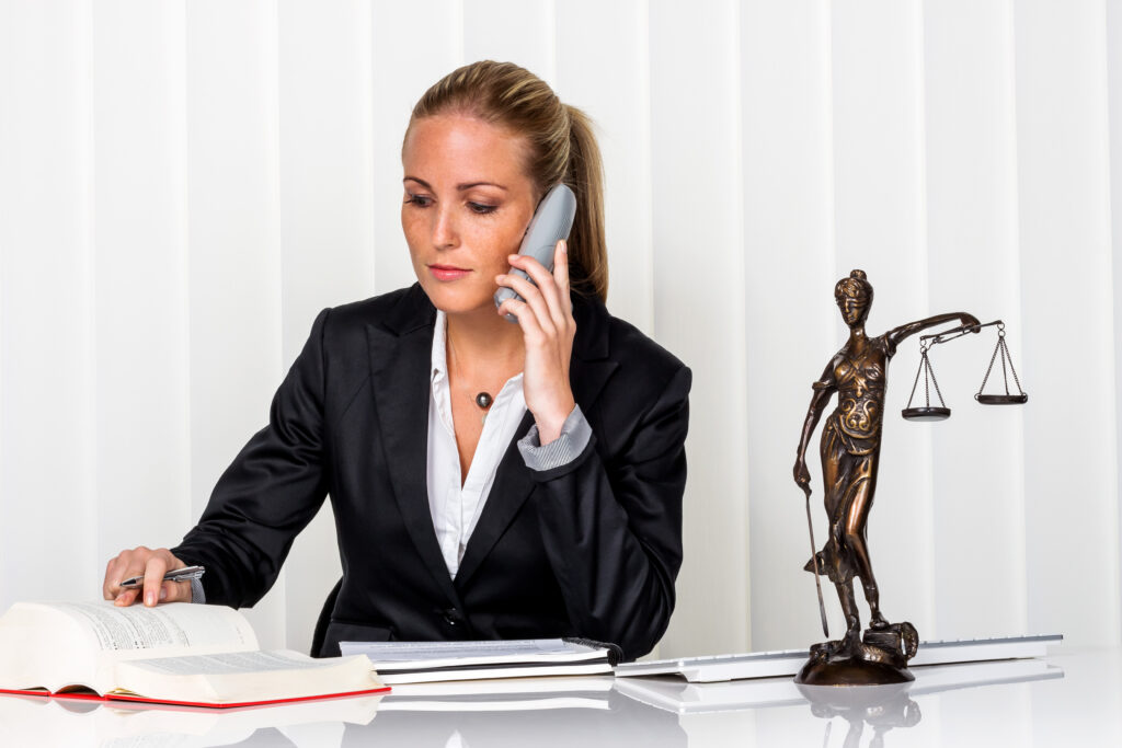 young female attorney talks on phone while seated at law office desk