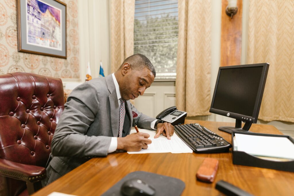 man in gray suit signing a document from a lawyer's office desk